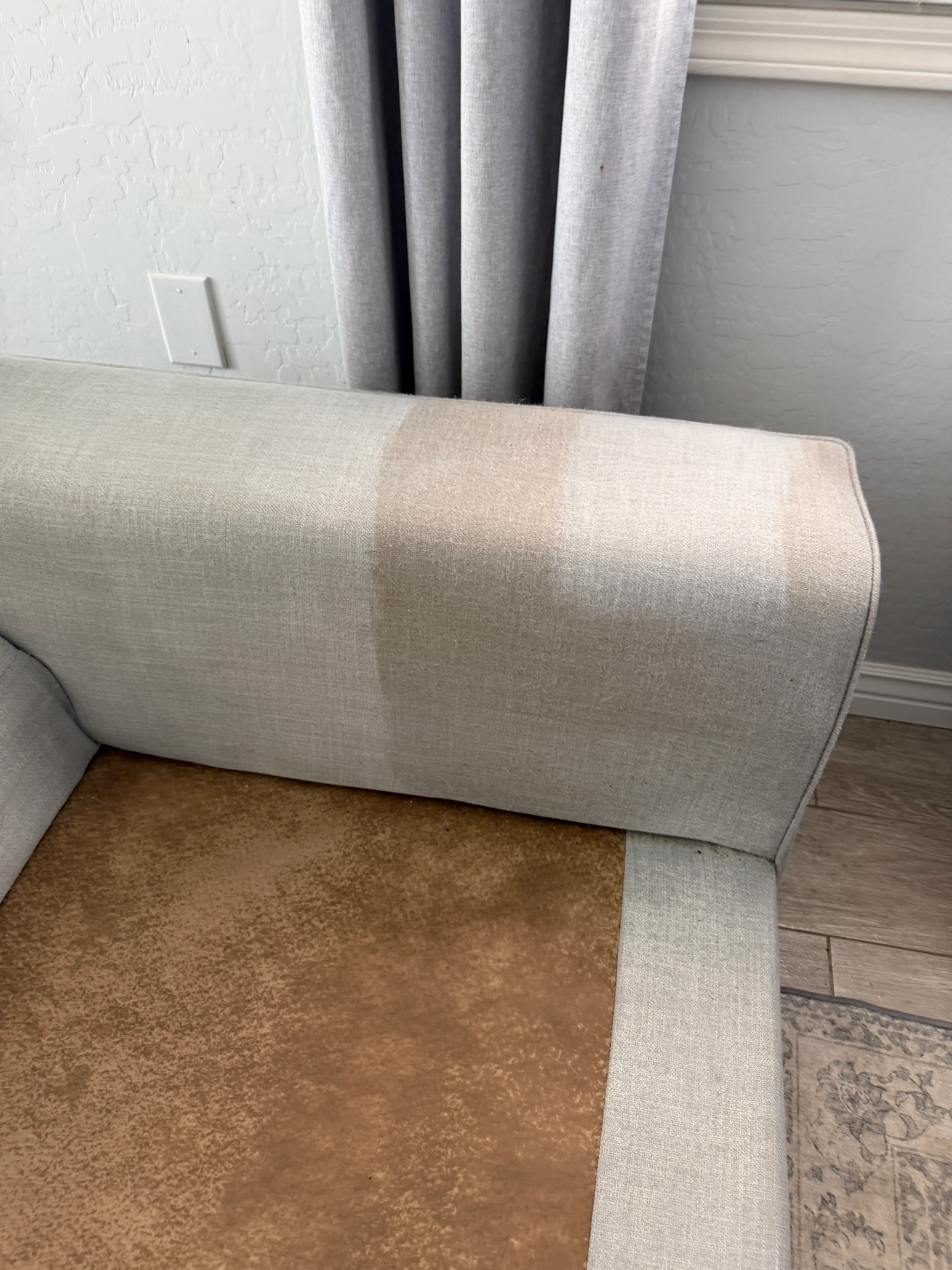 Light gray linen upholstered sofa with rolled armrest and piping detail after professional cleaning