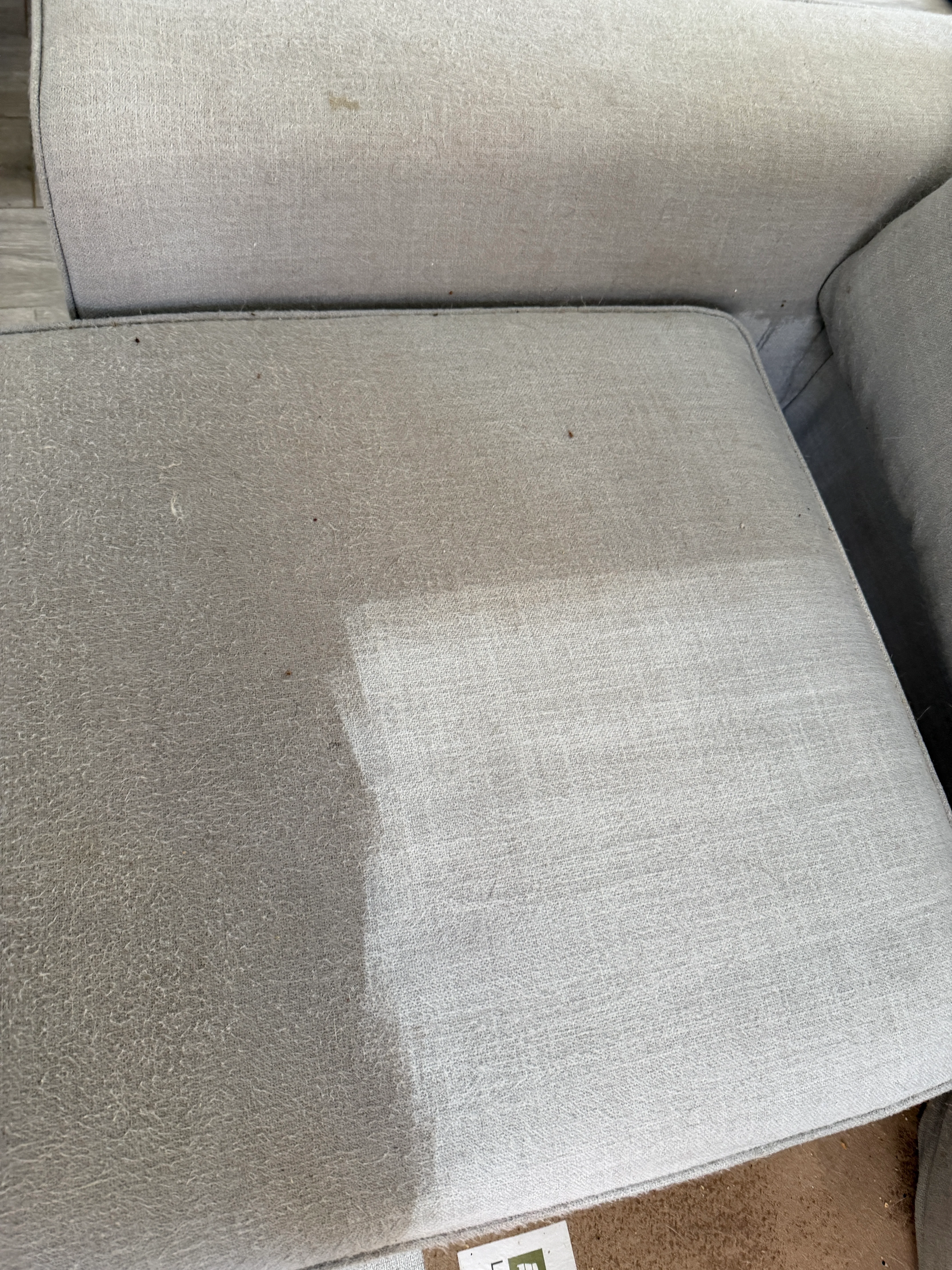 Light gray upholstered sofa cushion showing cleaned and restored fabric sections