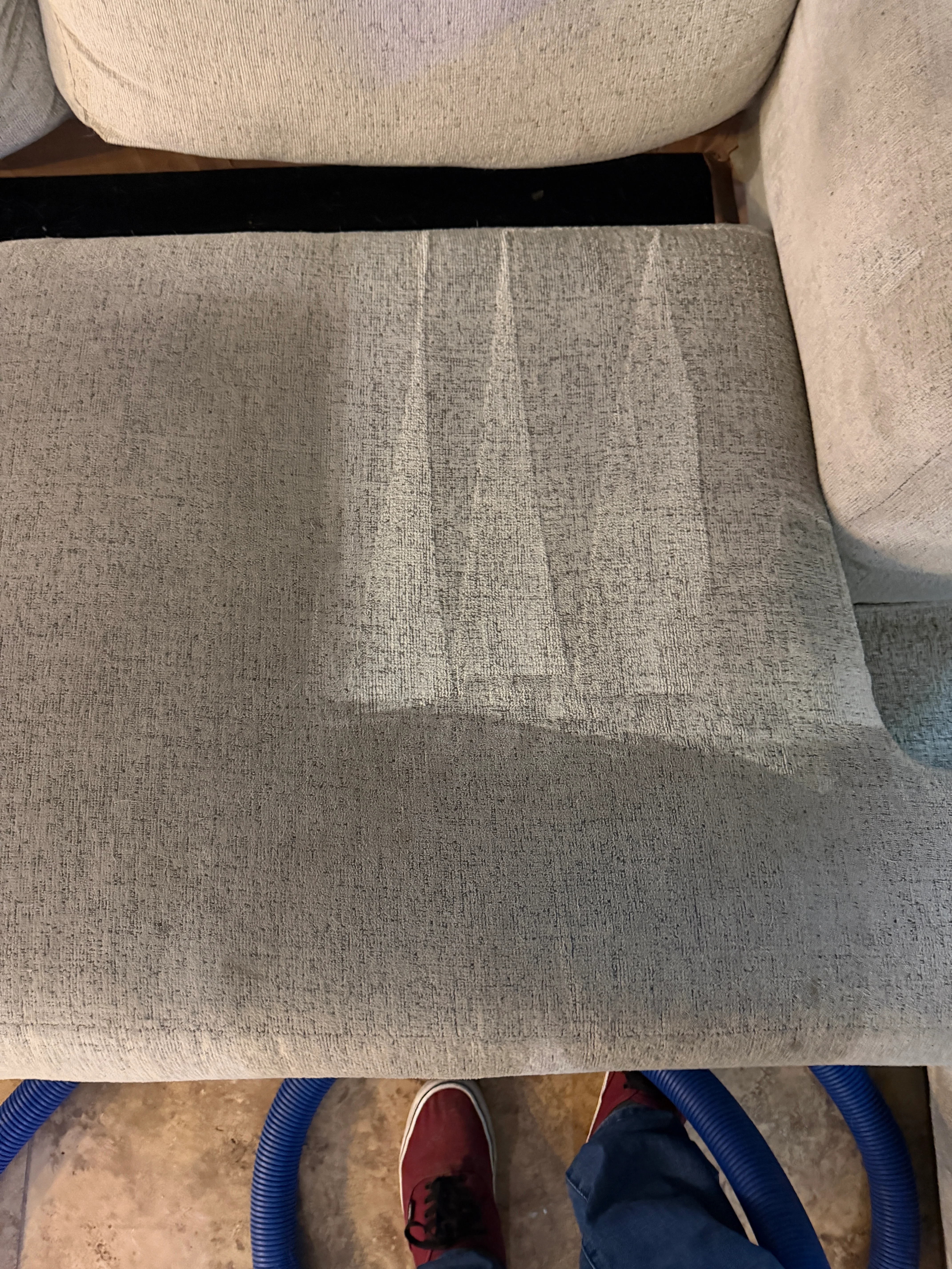 Beige upholstered sofa cushion showing cleaned and uncleaned sections of woven fabric